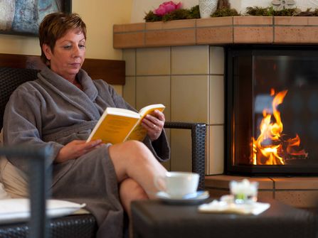 Bistro · Kaminecke · Frau liest Buch · Saunalandschaft der Sole-Therme Otterndorf