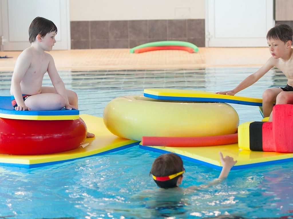 Nichtschwimmerbecken · Kinder spielen mit Matten und Reifen